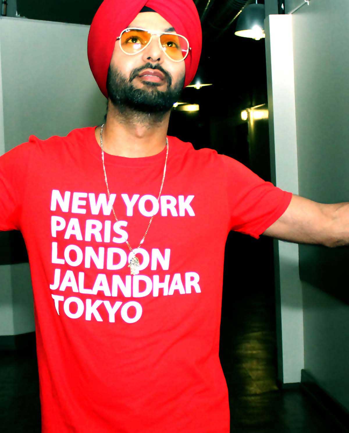 South Asian male wearing red fitted graphic design t.shirt with famous cities listed on front