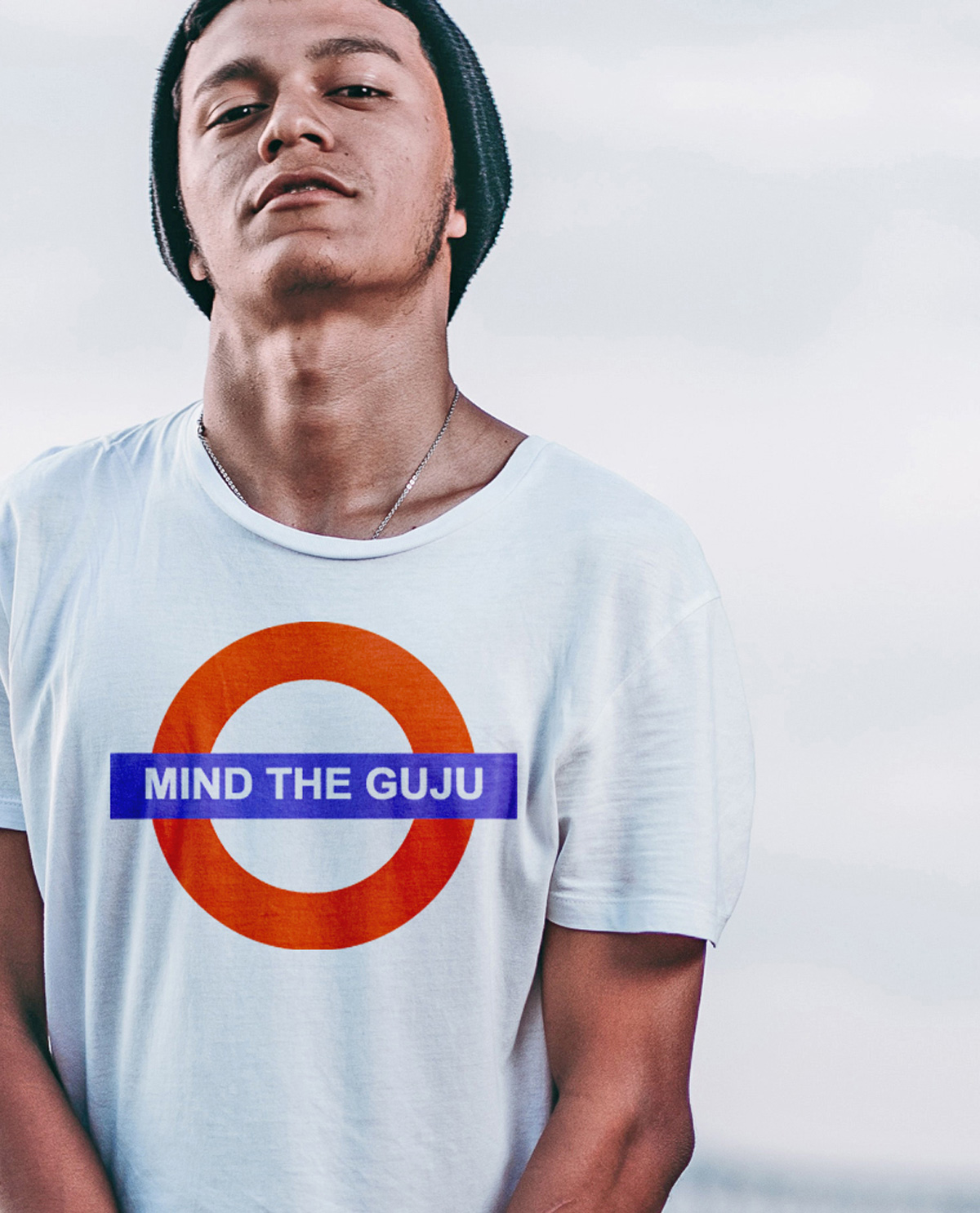 South Asian male model wearing white tshirt with graphic design print on front that says Mind The Guju